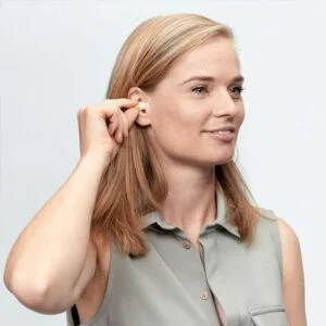 A lady holding her hand over her hearing protection in her right ear with her thumb and index finger.