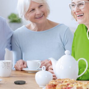 A group of senior individuals having a conversation over a cup of tea, using Roger microphones