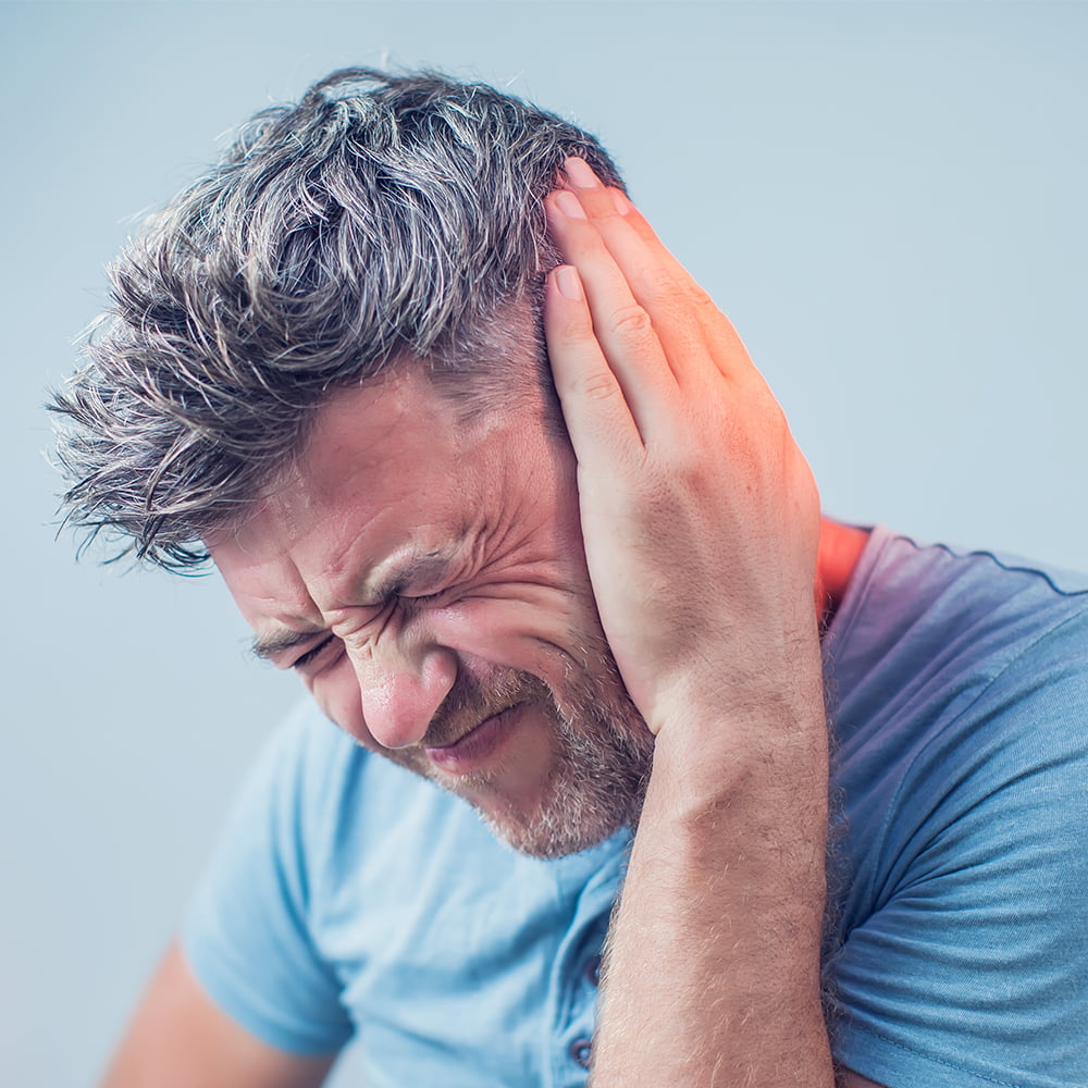 male having ear pain touching his painful head isolated on gray possibly tinnitus.