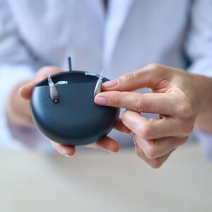 A hand holding a rechargeable hearing aids charging case.