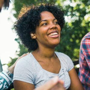 Young woman wearing a hearing aid with friends in park enjoying hearing in spring.