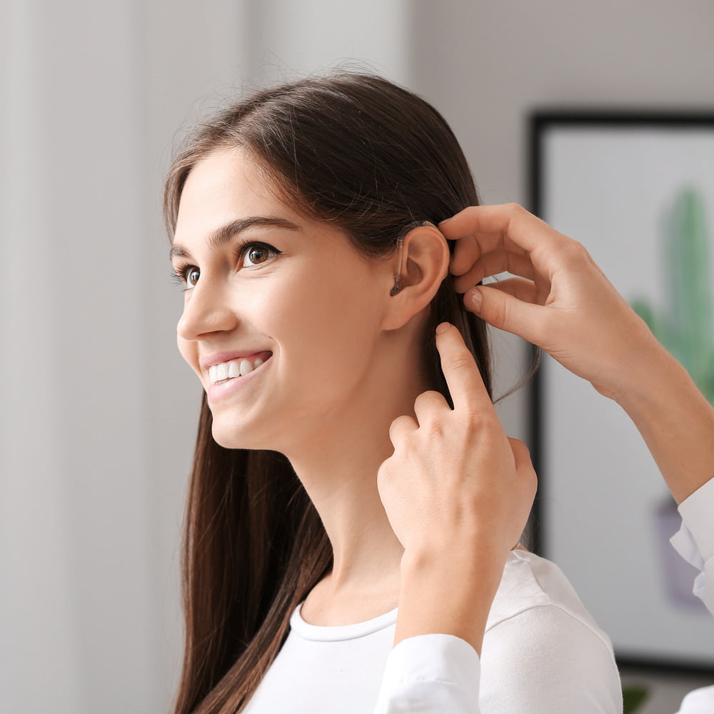Young woman having a hearing aid fitted along with earwax management